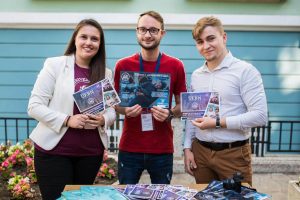 Two boys and a girl holding print materials