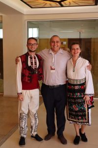 Two volunteers in traditional bulgarian clothes and a man smiling